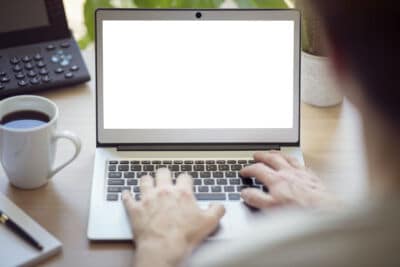 Man with laptop computer at office desk with blank screen
